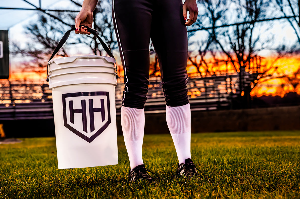 Softball player holding Home Run Hero bucket on softball field