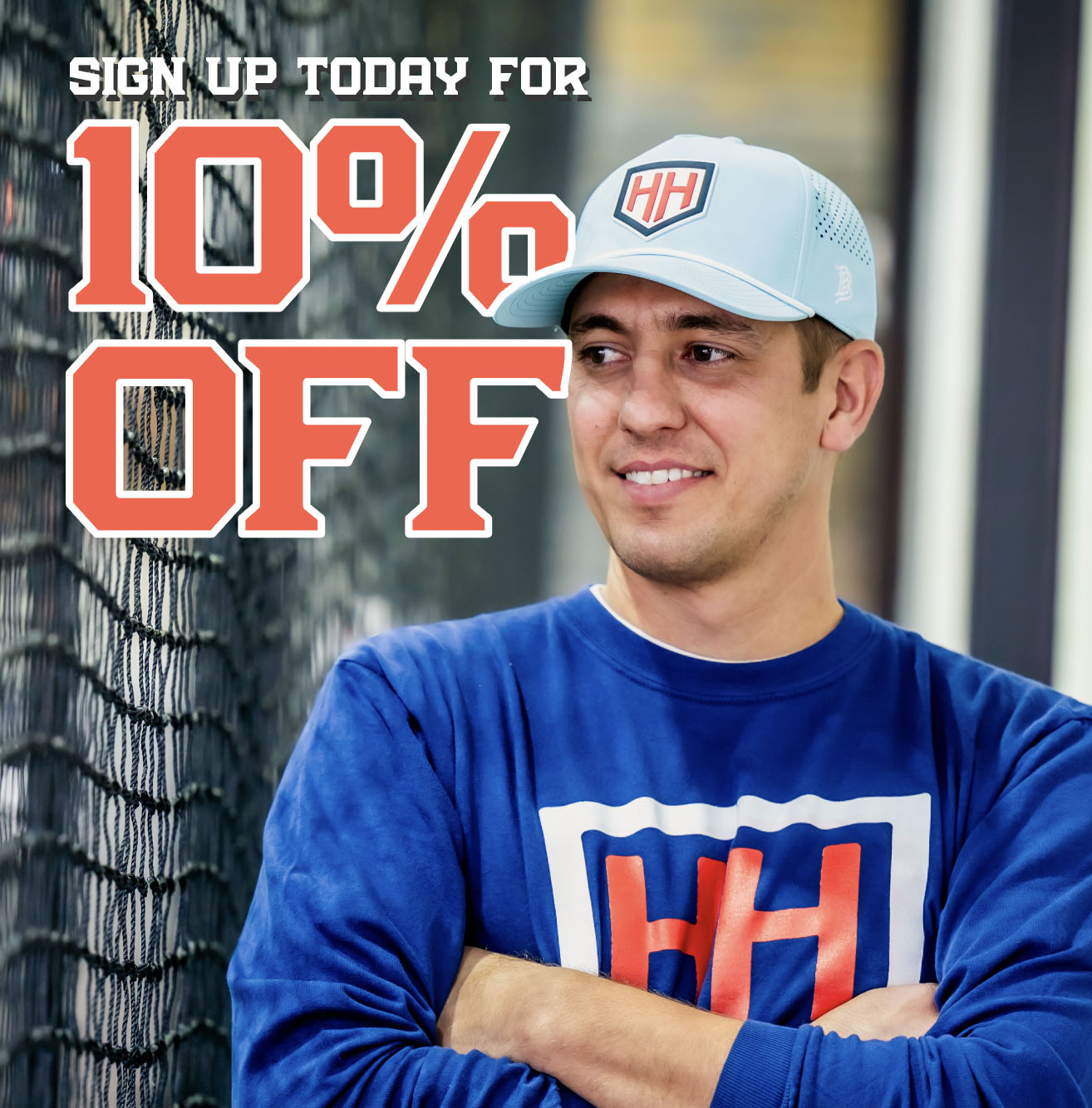 Coach Trey smiling toward batting cage wearing a Home Run Hero hat with text that says "Sign up today for 10% off"