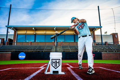 Baseball player hitting a baseball off of Home Run Hero tee outside
