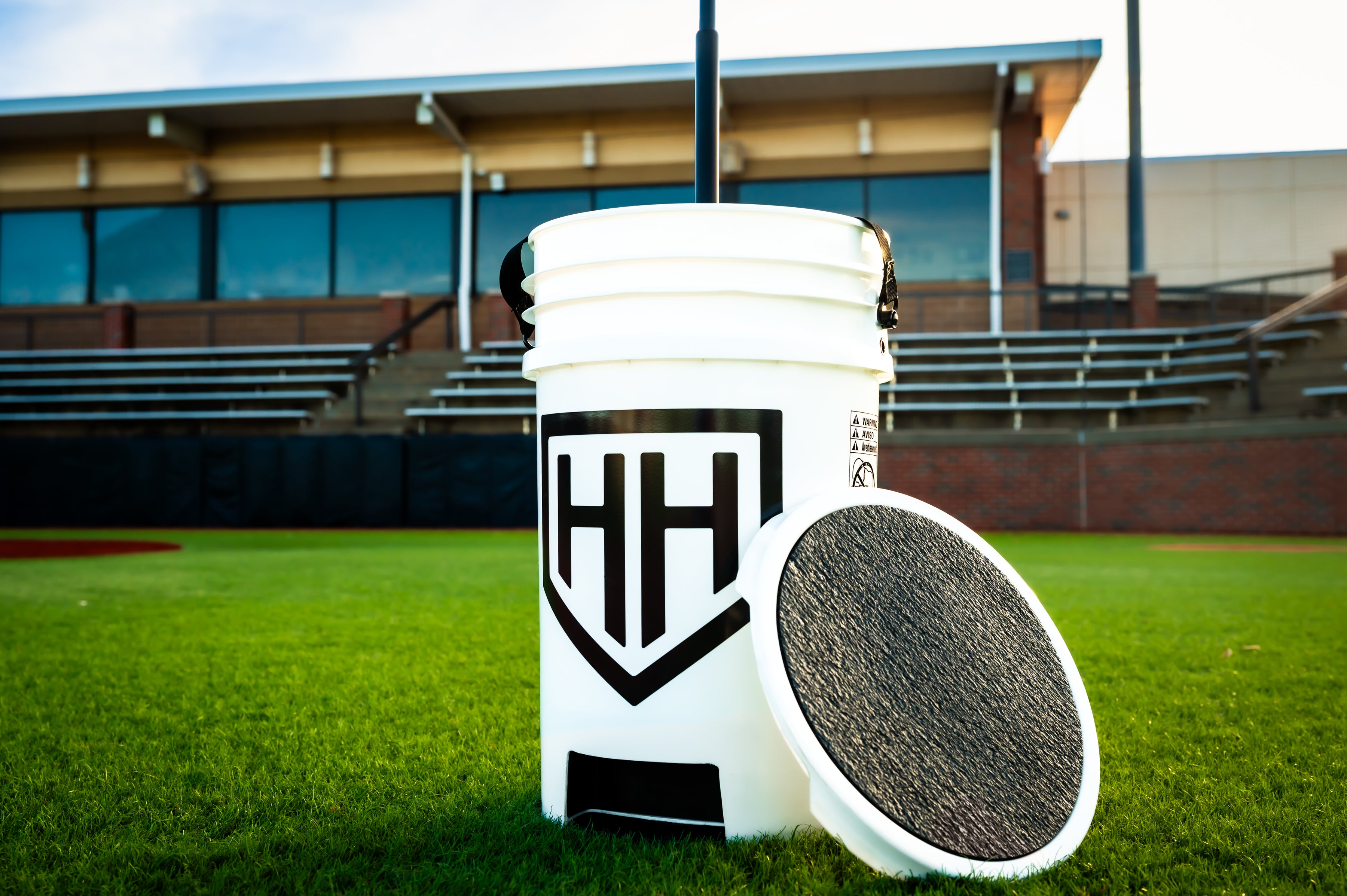 Home Run Hero baseball bucket sitting in grass with lid propped against bucket