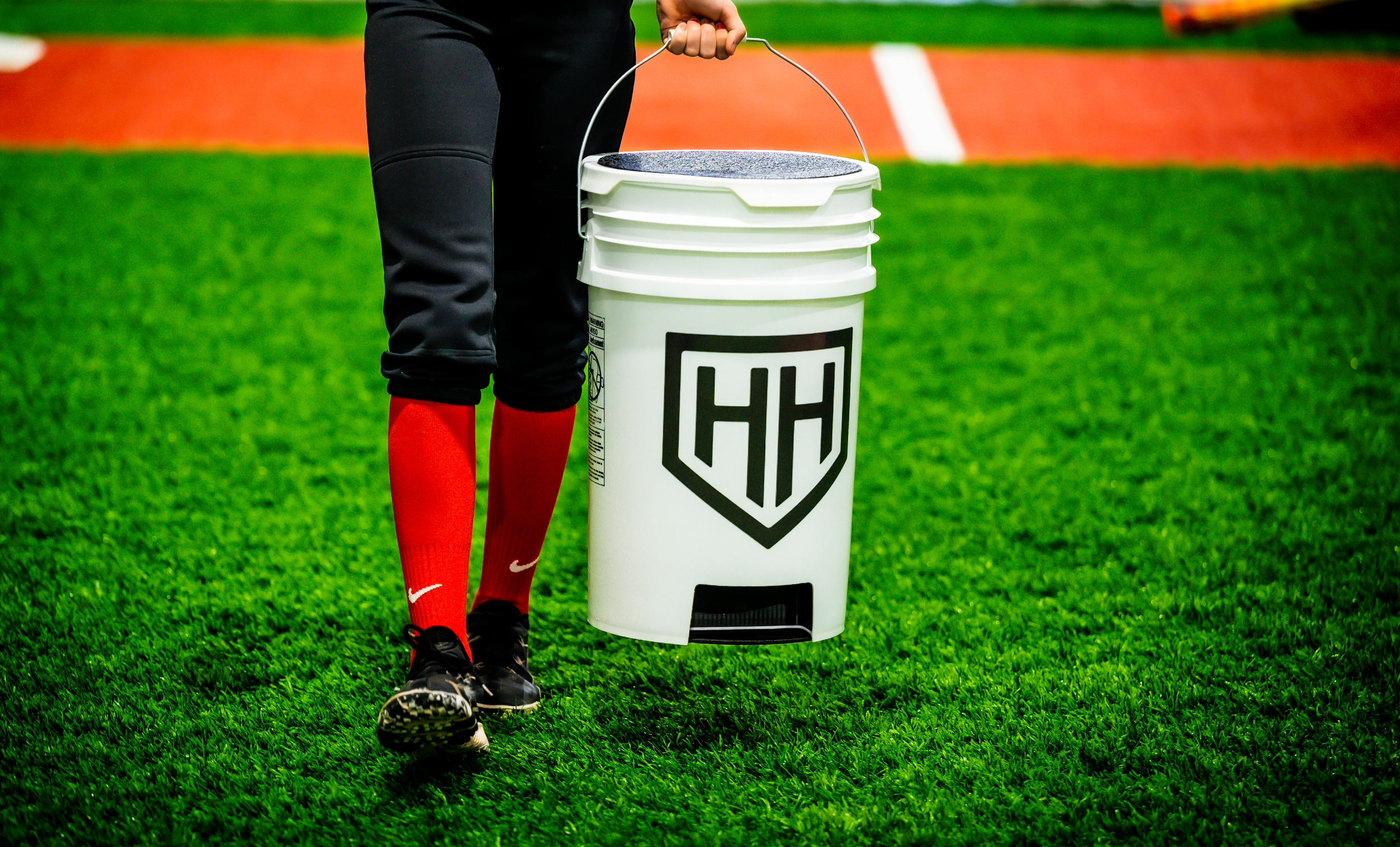 Softball player carrying Home Run Hero ball bucket